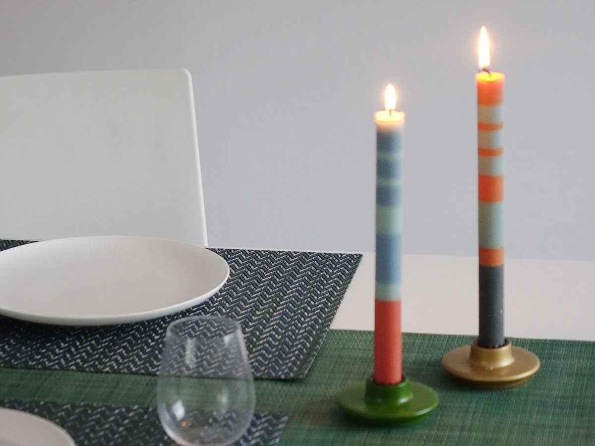 チルウィッチの緑のランチョンマットとテーブルランナーのアクセントに青・水色・朱色のボーダーキャンドルとオレンジ・グレイ・パープルのボーダーキャンドルと木製の緑とゴールドのキャンドルホルダーをアクセント