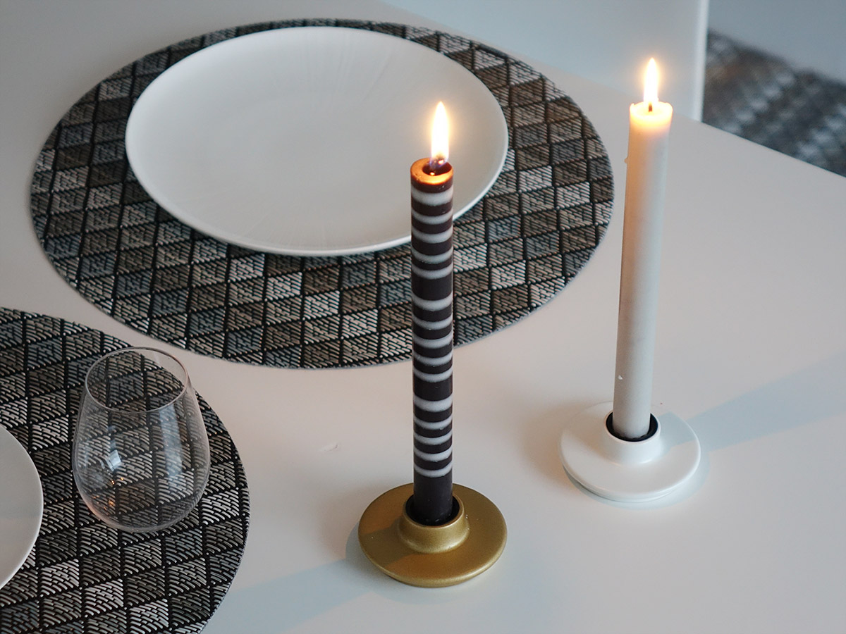 オリエンタルアーバンなモノトーンの円形ランチョンマットと白黒ボーダーのテーパーキャンドルと白とゴールドのキャンドルホルダーを組み合わせたテーブルコーディネート