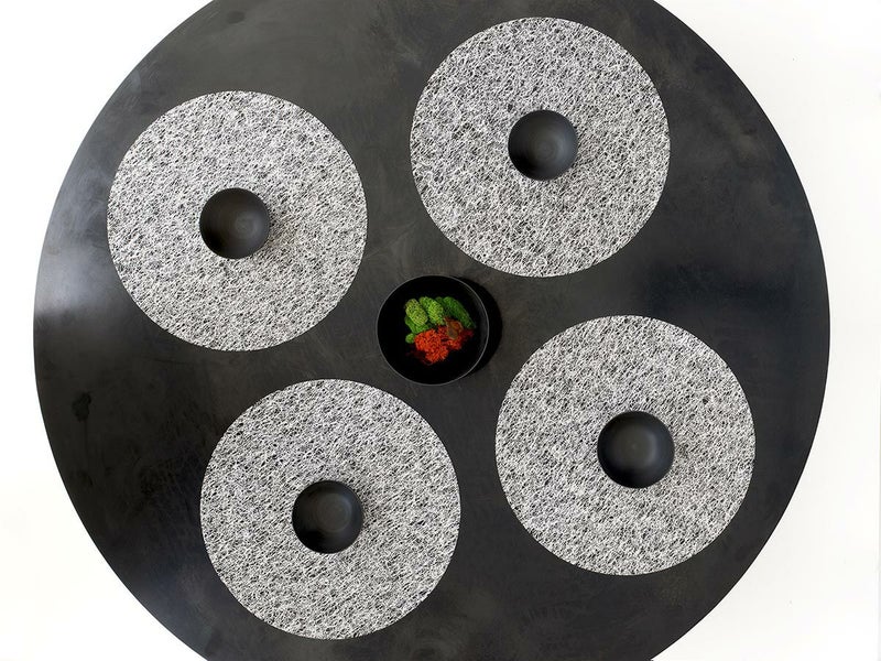 黒のラウンドテーブルに合わせたチルウィッチの丸型のランチョンマットの中で最もラグジュアリーなレースの繊細さと金属光沢を兼ね備えたシルバーのデザイン