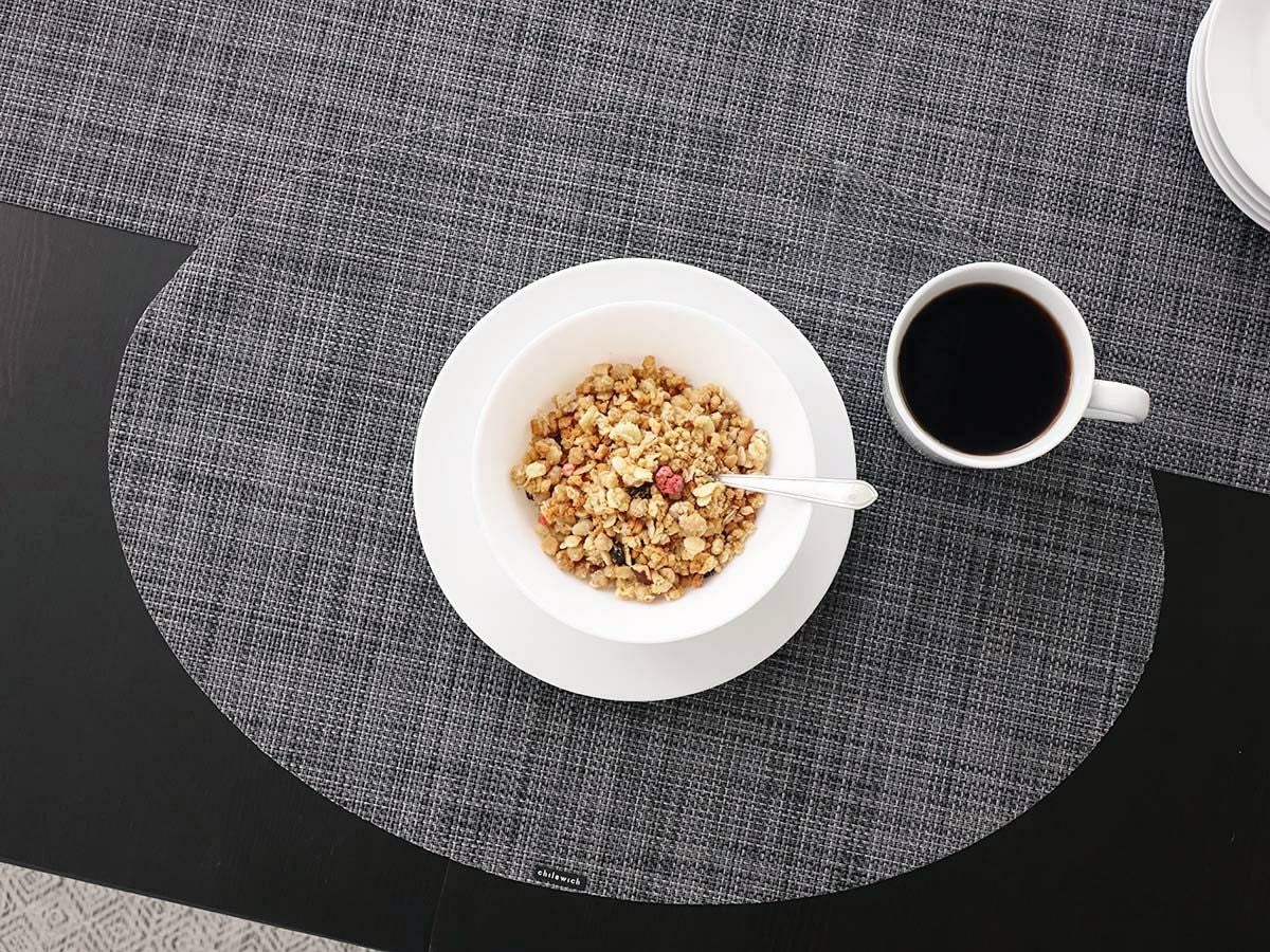 黒のテーブルに合わせた平織りの楕円形のダークグレイのチルウィッチのランチョンマット