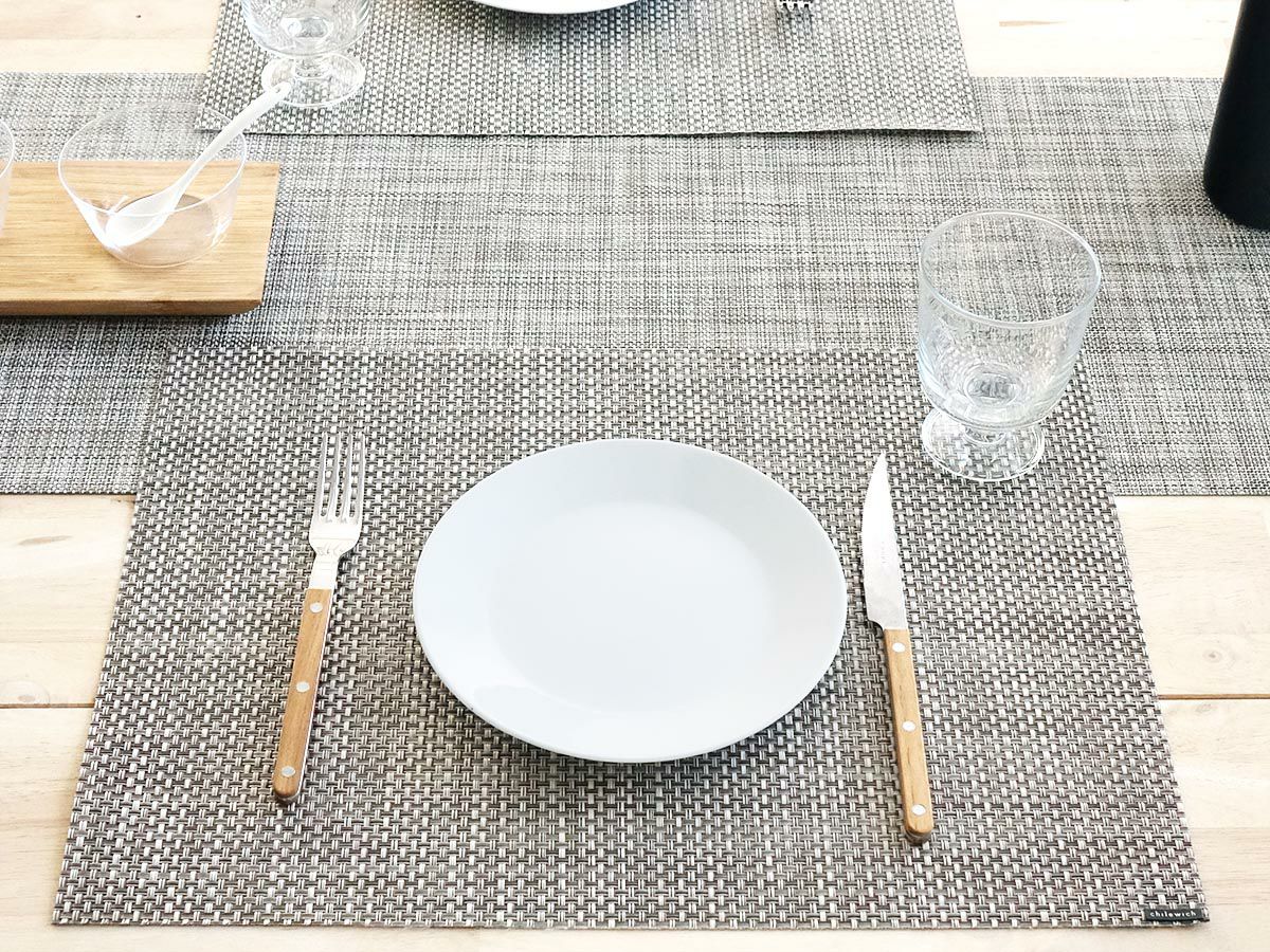 オークのテーブルに合わせたグレイとホワイトの平織りのランチョンマット