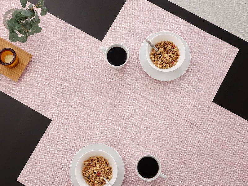 黒のテーブルに合わせた平織りのベビーピンクのテーブルランナーとランチョンマット