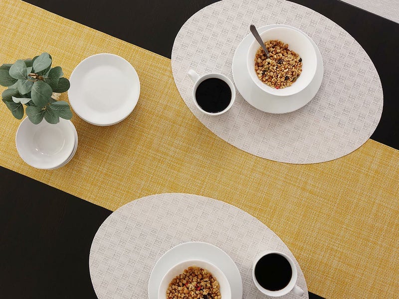 黒いテーブルに合わせた白色のレースの市松模様の楕円形のランチョンマットと黄色の無地のテーブルランナー　グラノーラとホットコーヒーのモーニング