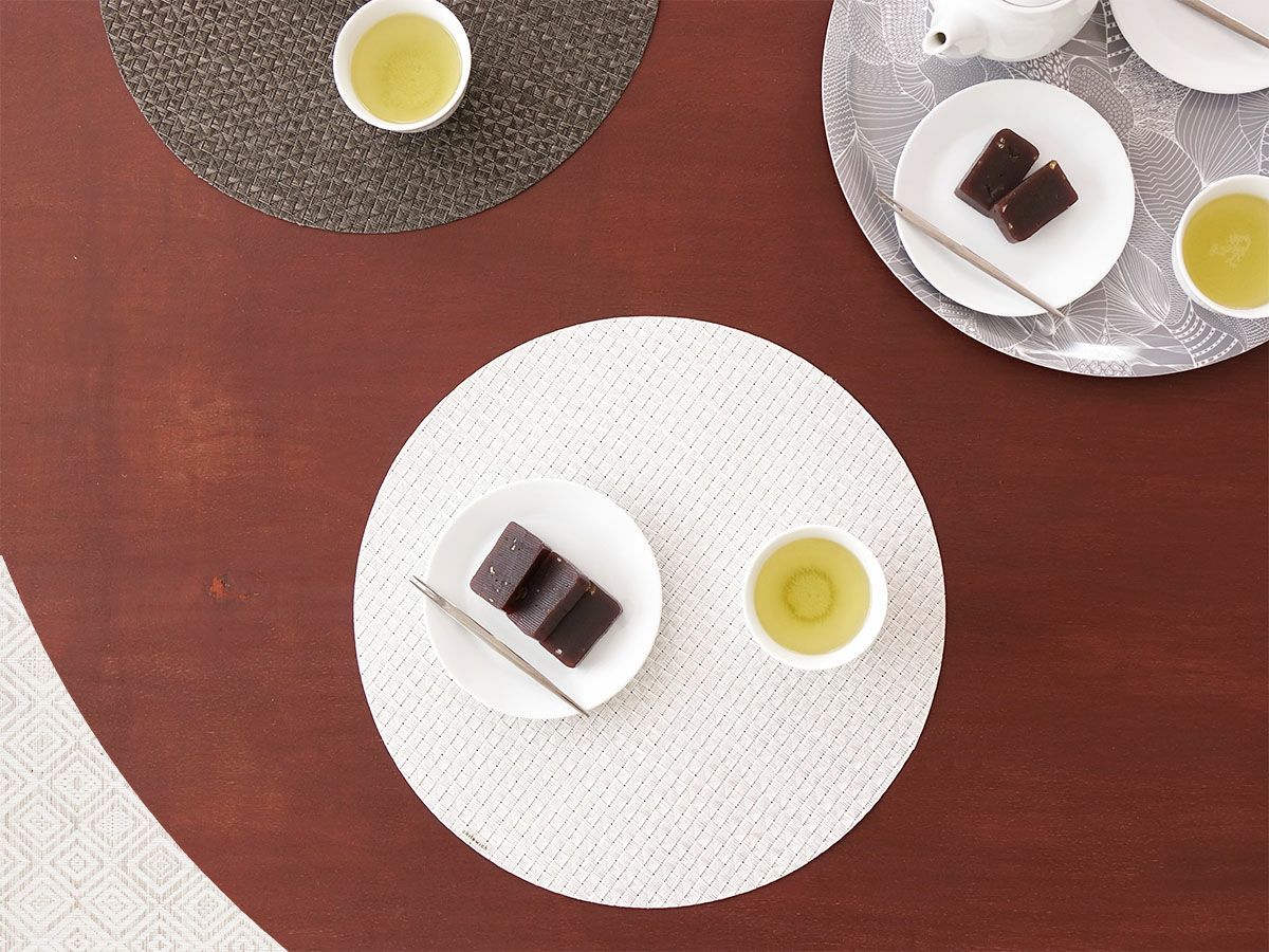 ダークブラウンのテーブルに合わせた真珠のような光沢のある白色で多面体のテクスチャーの円形ランチョンマット 羊羹と日本茶の喫茶タイム