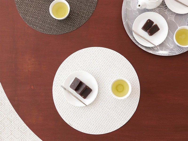 ダークブラウンのテーブルに合わせた真珠のような光沢のある白色で多面体のテクスチャーの円形ランチョンマット 羊羹と日本茶の喫茶タイム
